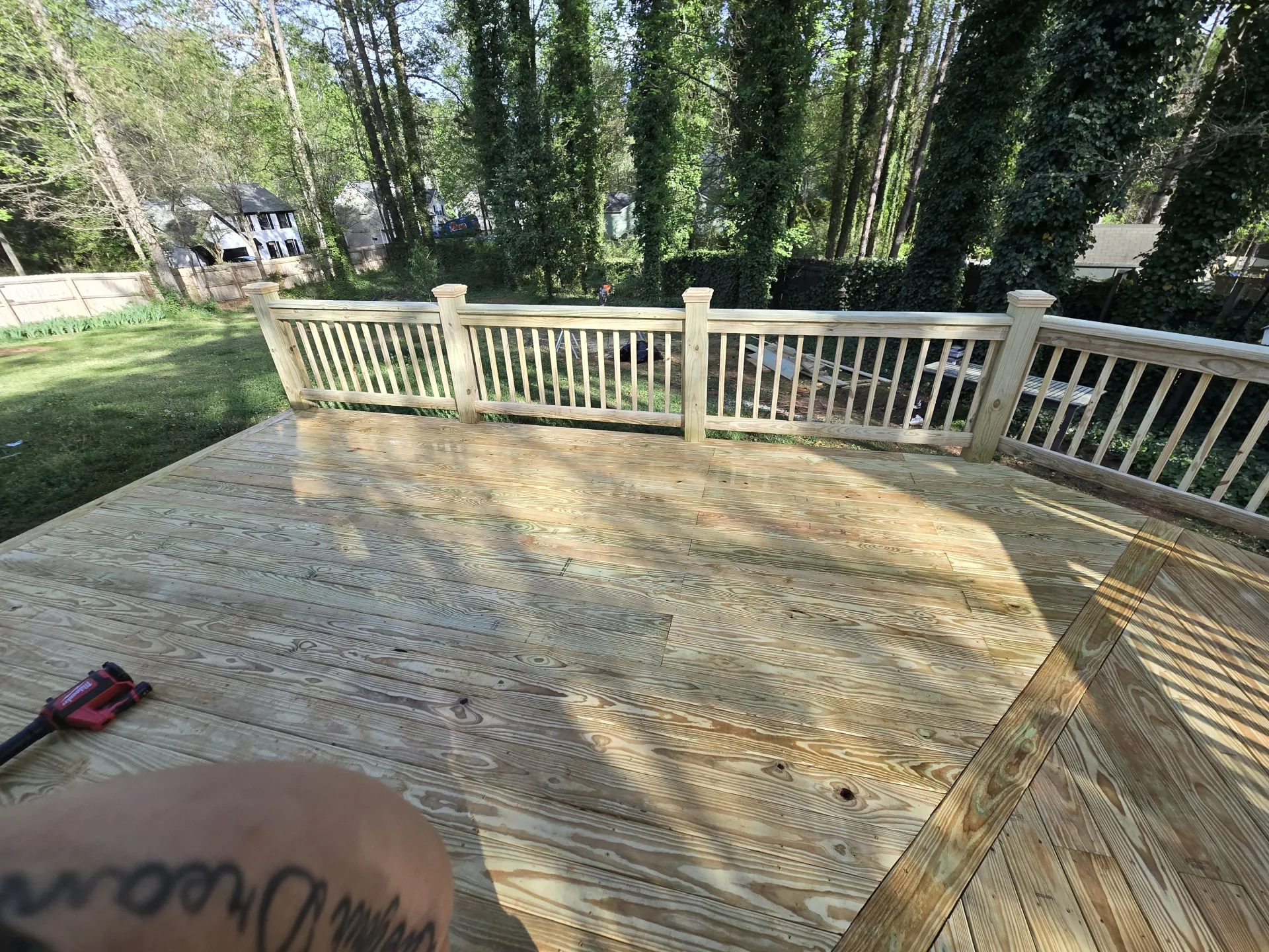 Deck surface with wood railings and green backdrop